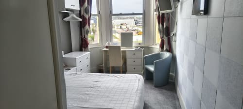 Deluxe Double Room at The Sands Hotel Paignton with sea view, bed, desk, TV, and coastal scenery from windows