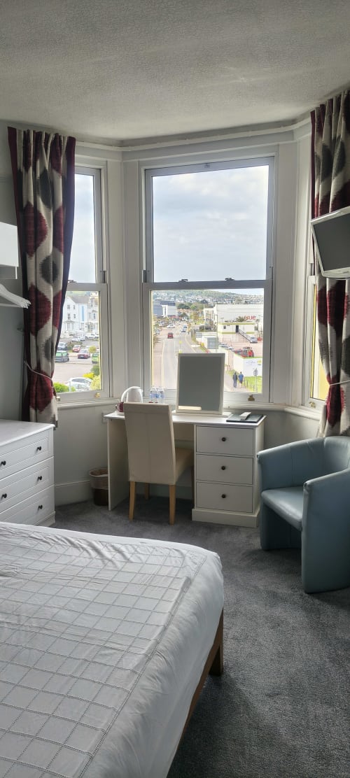 Deluxe double room with sea view at The Sands Hotel Paignton, featuring desk, chair, and panoramic coastal views
