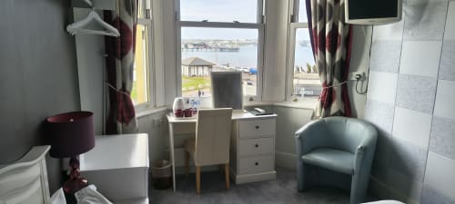 Deluxe double room with sea view at The Sands Hotel in Paignton, featuring desk, armchair, TV and coastal views