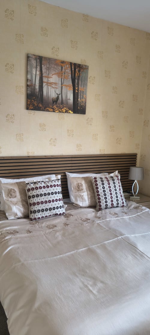 Deluxe Double Room at The Sands Hotel Paignton with woodland artwork above striped headboard and patterned pillows