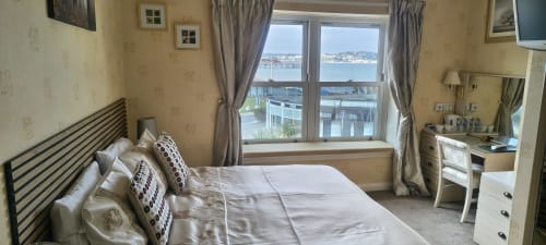 Deluxe double room with sea view at The Sands Hotel in Paignton, featuring bed, desk, and coastal views