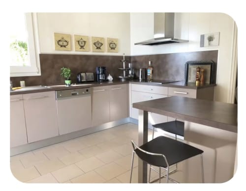 Cucina moderna con piani di lavoro scuri, armadi bianchi e bancone colazione nella villa di lusso di Conciergerie De Porticcio