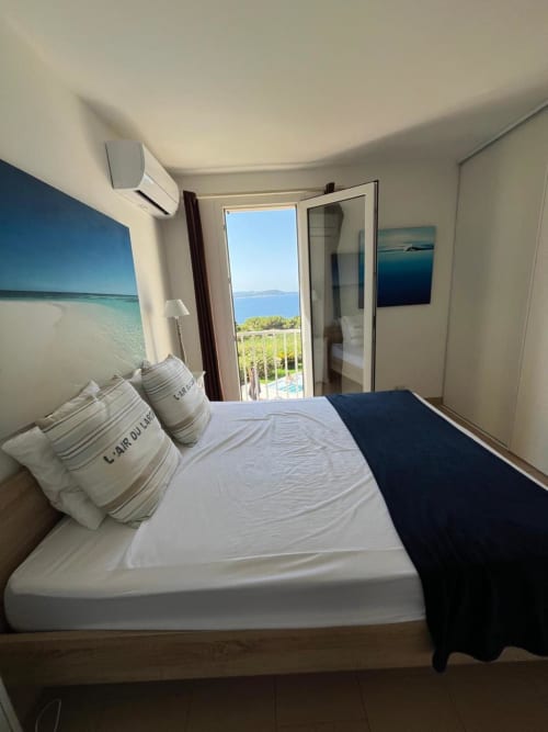 Camera da letto con balcone vista mare alla villa Conciergerie De Porticcio in Corsica, con letto matrimoniale e vista oceano