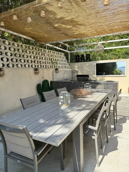 Terrazza esterna moderna con vista sul mare presso la villa Conciergerie De Porticcio, con tavolo e sedie in legno sotto una trama tessuta