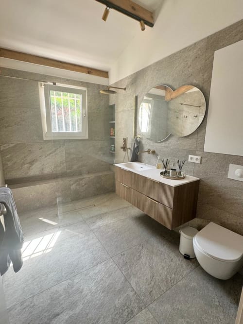 Bagno moderno nella villa Conciergerie De Porticcio con piastrelle grigie, mobile in legno, specchio rotondo e zona doccia
