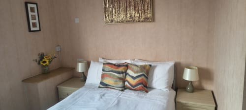 Triple room at The Sands Hotel, Paignton with double bed, colorful pillows, bedside lamps, and framed wall art