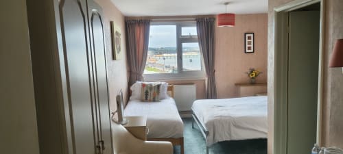 Triple room with sea view at The Sands Hotel Paignton, featuring two beds, window overlooking coastline, and modern amenities