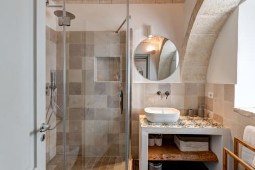 Lussuoso bagno nella villa Trulli Gianpaolo a Bari, con doccia moderna, specchio rotondo e lavabo in pietra