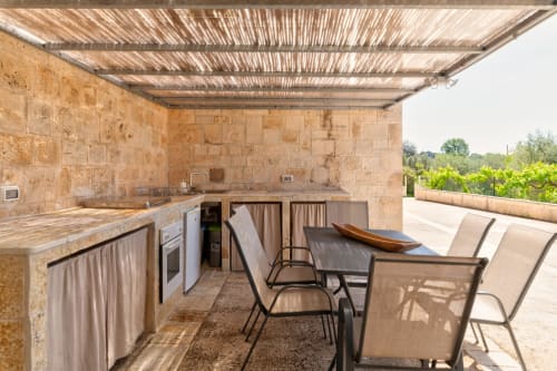 Cucina e zona pranzo esterna della villa Trulli Life a Bari con banconi in pietra e vista sulla campagna
