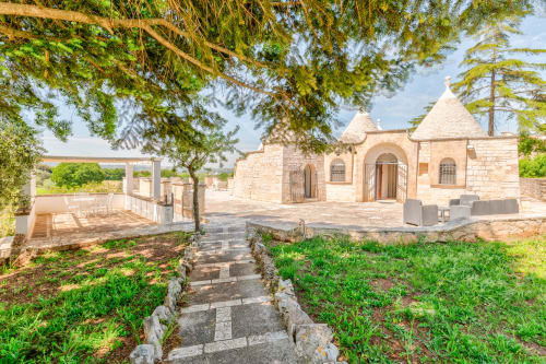 Villa Trullo Il Sassofono presso Trulli Life hotel a Bari con tetto conico in pietra, terrazza e giardini curati sotto gli alberi