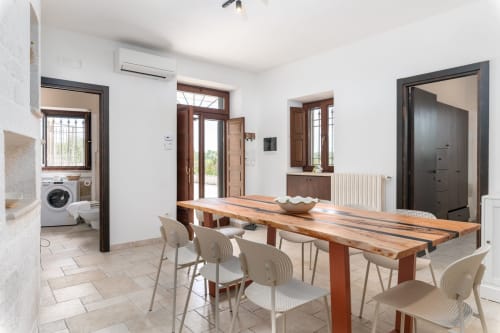 Moderna zona pranzo nella villa Trullo Il Sassofono a Trulli Life, Bari, con tavolo in legno e accesso alla cucina