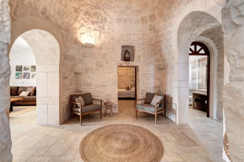 Interno della villa Trullo tradizionale a Trulli Life, Bari, con arcate in pietra, arredi rustici e tappeto rotondo in iuta