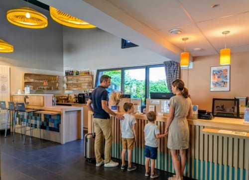 Famille à la réception de l'hôtel La Verriaire à Chanverrie, France avec un espace d'accueil moderne et un éclairage ambiant