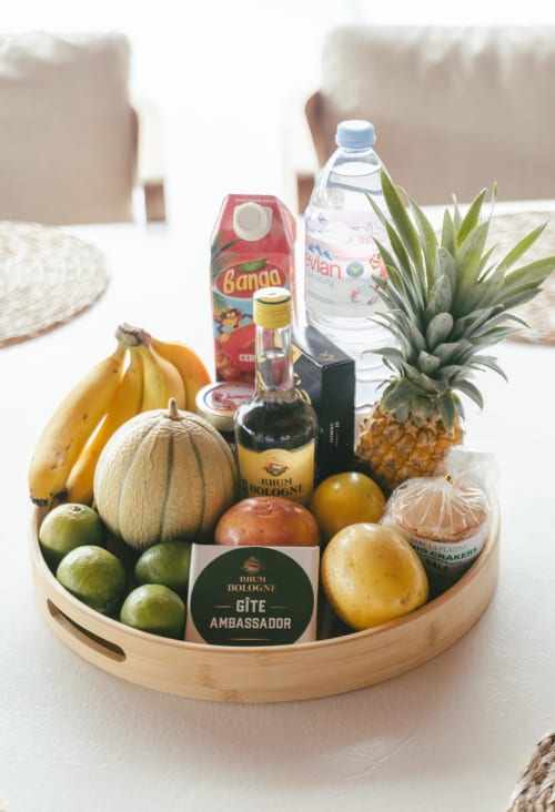 Panier cadeau de bienvenue luxe avec fruits tropicaux, eau Evian, rhum et ananas frais à la villa Blue Horizon Collection
