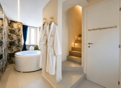 Luxury bathroom at HomeholidaySanremo with circular jacuzzi tub, white robes, and ambient lighting in Sanremo