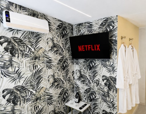 Chambre moderne à HomeholidaySanremo avec papier peint botanique noir, climatiseur mural, TV Netflix et décoration blanche