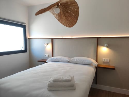Dormitorio moderno en el apartamento de lujo Nido Anaga en Tenerife con lámpara de techo tejida e iluminación ambiental cálida
