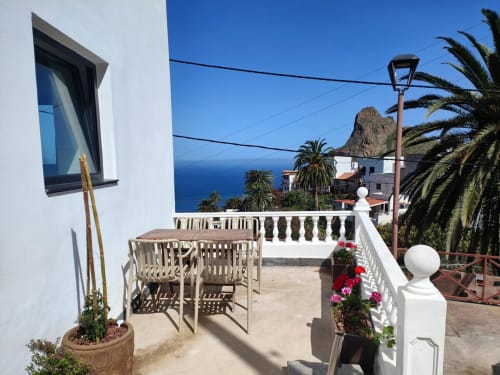 Soleada terraza de Nido Anaga con vistas al mar, muebles de madera y palmeras en Tenerife