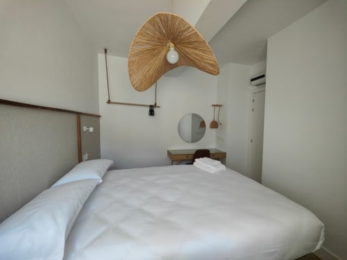 Dormitorio moderno en Nido Anaga, apartamento de lujo en Tenerife, con lámpara colgante tejida y decoración minimalista