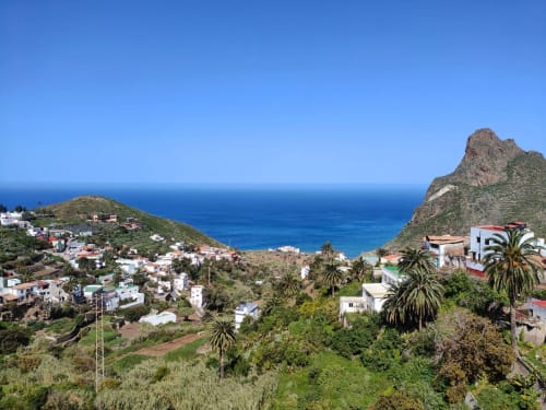 Pintoresco pueblo costero entre las montañas de Anaga, con casas blancas, palmeras y un cristalino mar Mediterráneo en Tenerife