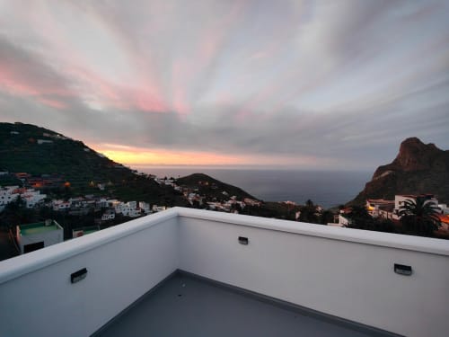 Vista del atardecer desde la terraza de Nido Anaga con edificios blancos y montañas de Tenerife