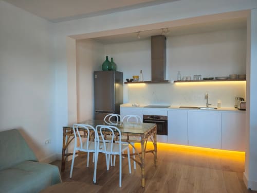 Modern kitchen and dining area at Nido Anaga apartment in Santa Cruz de Tenerife with white chairs and warm lighting
