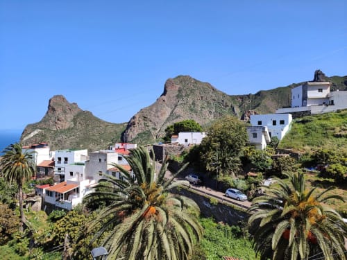 Nido Anaga hillside village with white buildings, rocky peaks, palm trees overlooking sea, Santa Cruz Tenerife