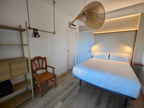 Modern bedroom at Nido Anaga in Tenerife with queen bed, wooden shelving, woven pendant lamp, and minimalist design