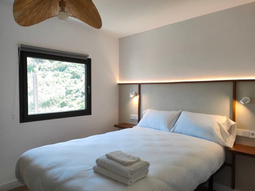 Dormitorio moderno en Nido Anaga con ventanal panorámico al mar, ventilador de techo de madera y diseño minimalista en Tenerife