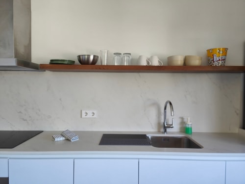 Elegante fregadero de cocina moderna con salpicadero de mármol y estantería de madera con loza en el apartamento Nido Anaga, Tenerife