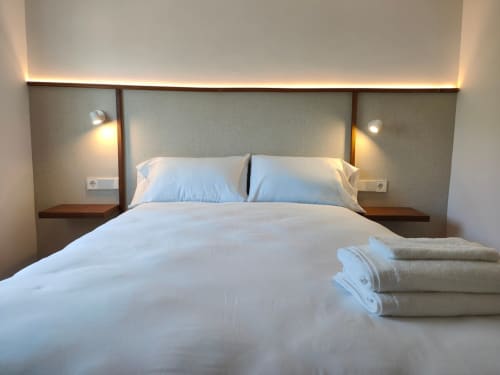 Habitación moderna en Nido Anaga con ropa de cama blanca, almohadas azules, iluminación ambiental y toallas dobladas en Santa Cruz de Tenerife