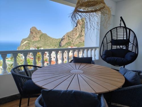 Romantic balcony at Nido Anaga with round table, hanging chair, sea views and dramatic cliffs in Tenerife