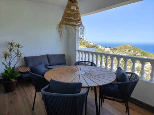 Nido Anaga romantic balcony apartment with sea view, round dining table, black wicker chairs, and Mediterranean coastal