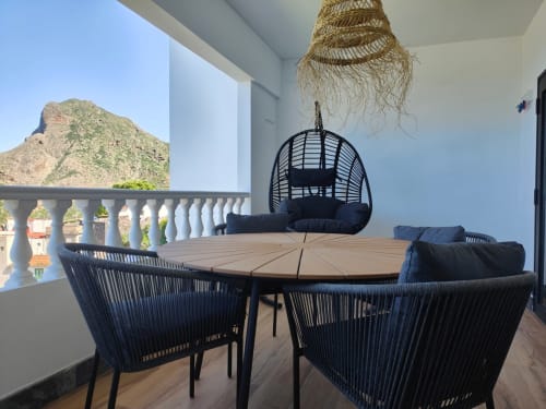 Romantic balcony at Nido Anaga with round dining table, black woven chairs, hanging pod seat, and mountain views in Tenerife