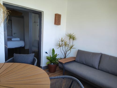 Nido Anaga romantic apartment balcony in Tenerife with gray sofa, wooden furniture, and potted plants
