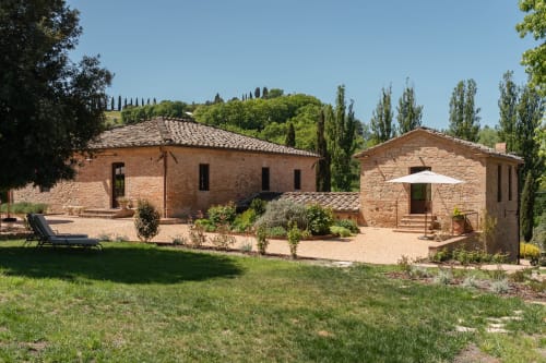 Rustic brick farmhouse at Agriturismo La Frattina near Siena, Italy with terracotta roof, manicured gardens and cypress trees