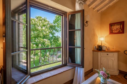 Granaia room at Agriturismo La Frattina in Siena with open balcony doors overlooking green gardens and countryside