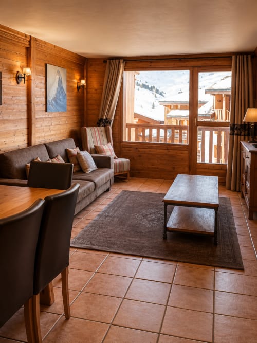 Appartement de luxe alpin au Chalet des Cimes avec vue montagne, mobilier en bois, coin salon confortable et balcon
