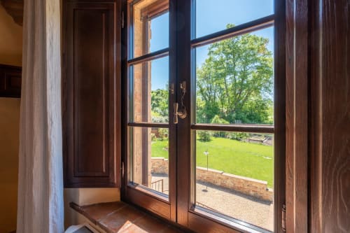 Open wooden doors at Agriturismo La Frattina in Siena reveal lush green gardens and countryside views from the Mimosa room