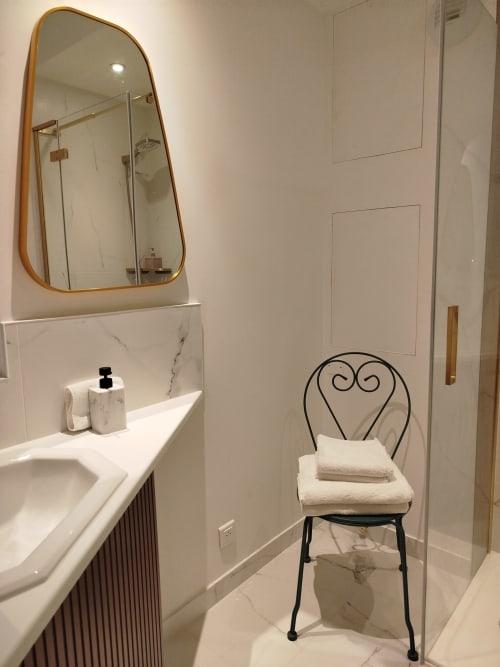 Salle de bains moderne à la Villa Voltaire à Clamart avec lavabo en marbre, miroir doré et chaise décoration