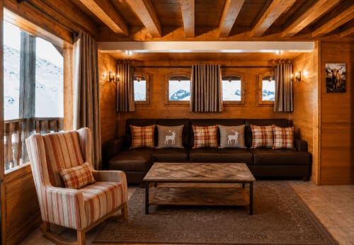 Salon rustique d'un chalet alpin avec poutres en bois, canapé marron et vue sur les montagnes au Chalet des Cimes, Savoie