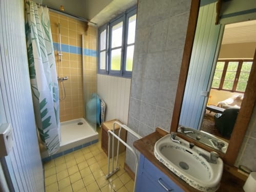 Shared bathroom at Le Lama Zébré BnB in Penmarch with shower, sink, and yellow tile flooring