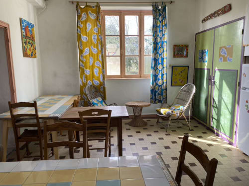 Bright communal room at Le Lama Zébré B&B in Penmarch featuring wooden furniture, patterned curtains, and shared dining and
