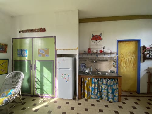 Colorful kitchen area in Chambre Marsupilami at Le Lama Zébré, a Penmarch B&B, featuring green cabinets, white fridge, and