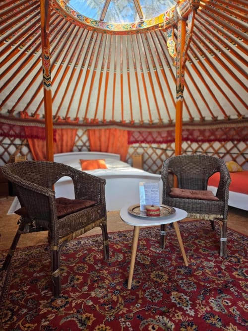 Intérieur de yourte mongole à Destination Ailleurs à Castellane avec fauteuils en rotin, cheminée et décoration traditionnelle