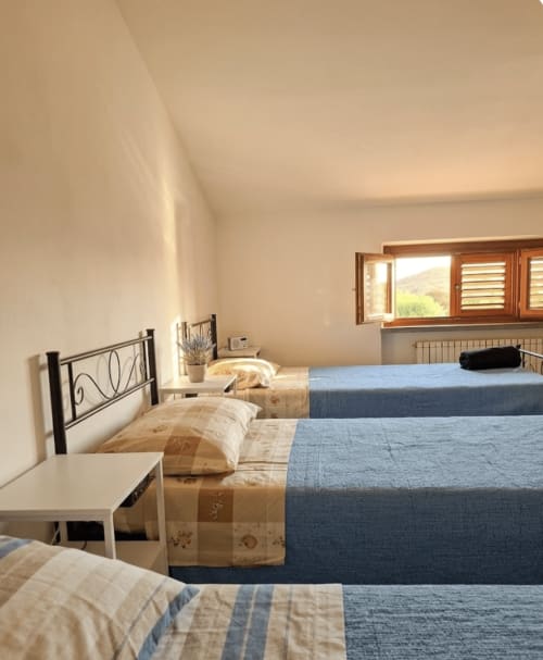 Male dormitory beds at B&B Rio Grande hostel in Massarosa, Italy with wooden frame beds and blue bedding