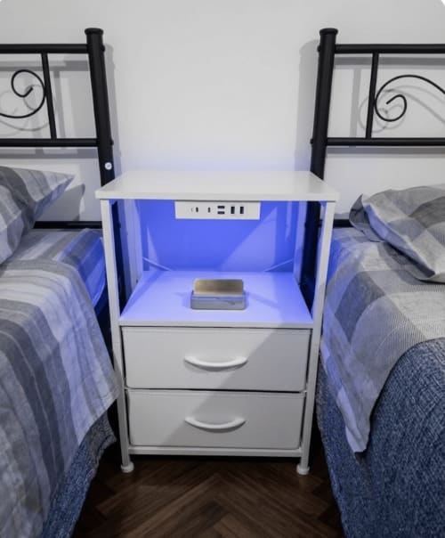 White nightstand with blue LED light between two hostel beds at B&B Rio Grande in Massarosa