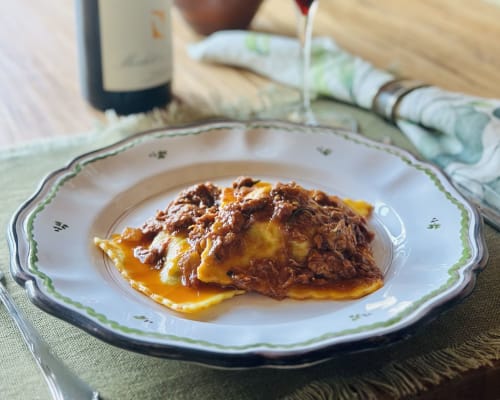 Braised meat over creamy polenta served on decorative plate at Agriturismo La Frattina, Siena