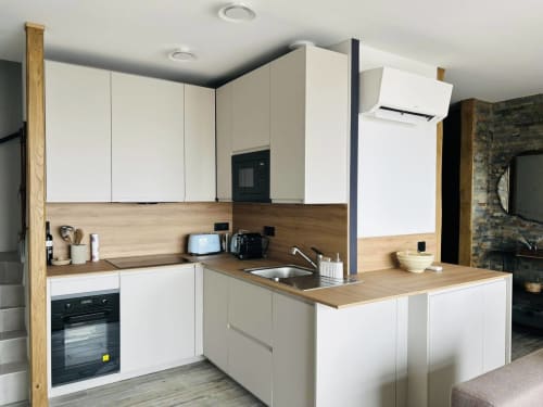Cuisine moderne du Chalet CIRELINE Risoul avec meubles blancs, plan de travail en bois et électroménagers intégrés