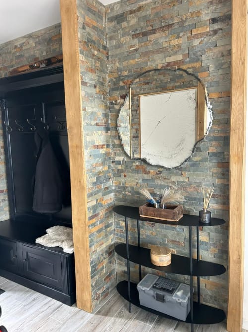Entrée moderne du Chalet Cireline Risoul avec mur en brique, miroir rond, étagères noires et détails en poutre bois